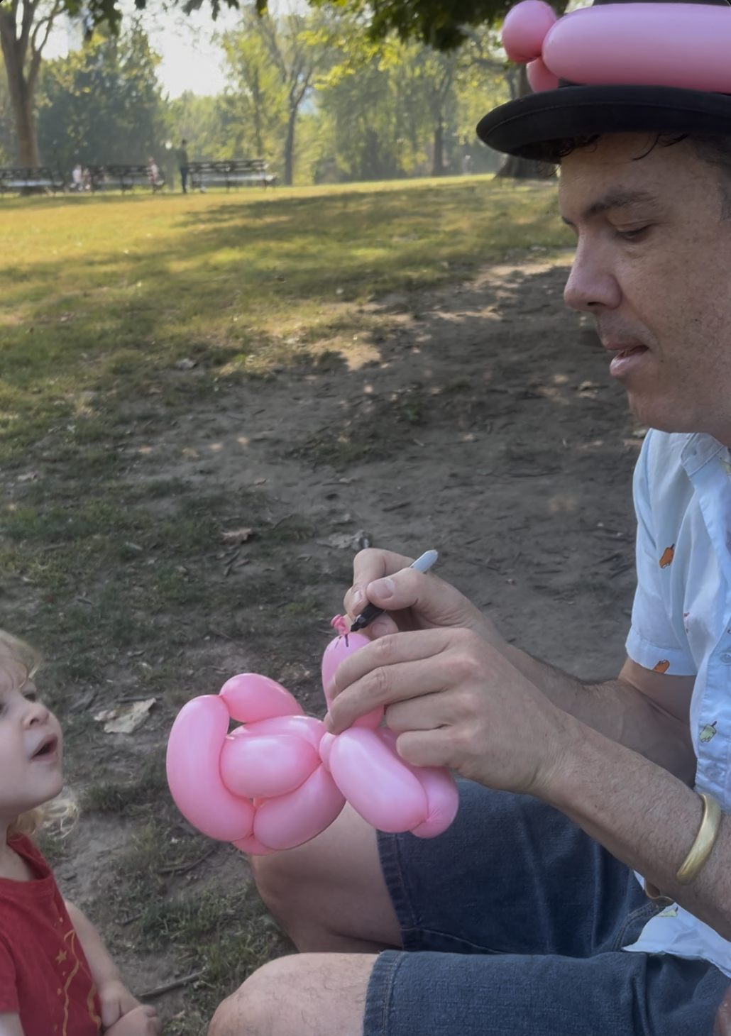 A balloon artist making a pink balloon rabbit sculpture for a child's birthday