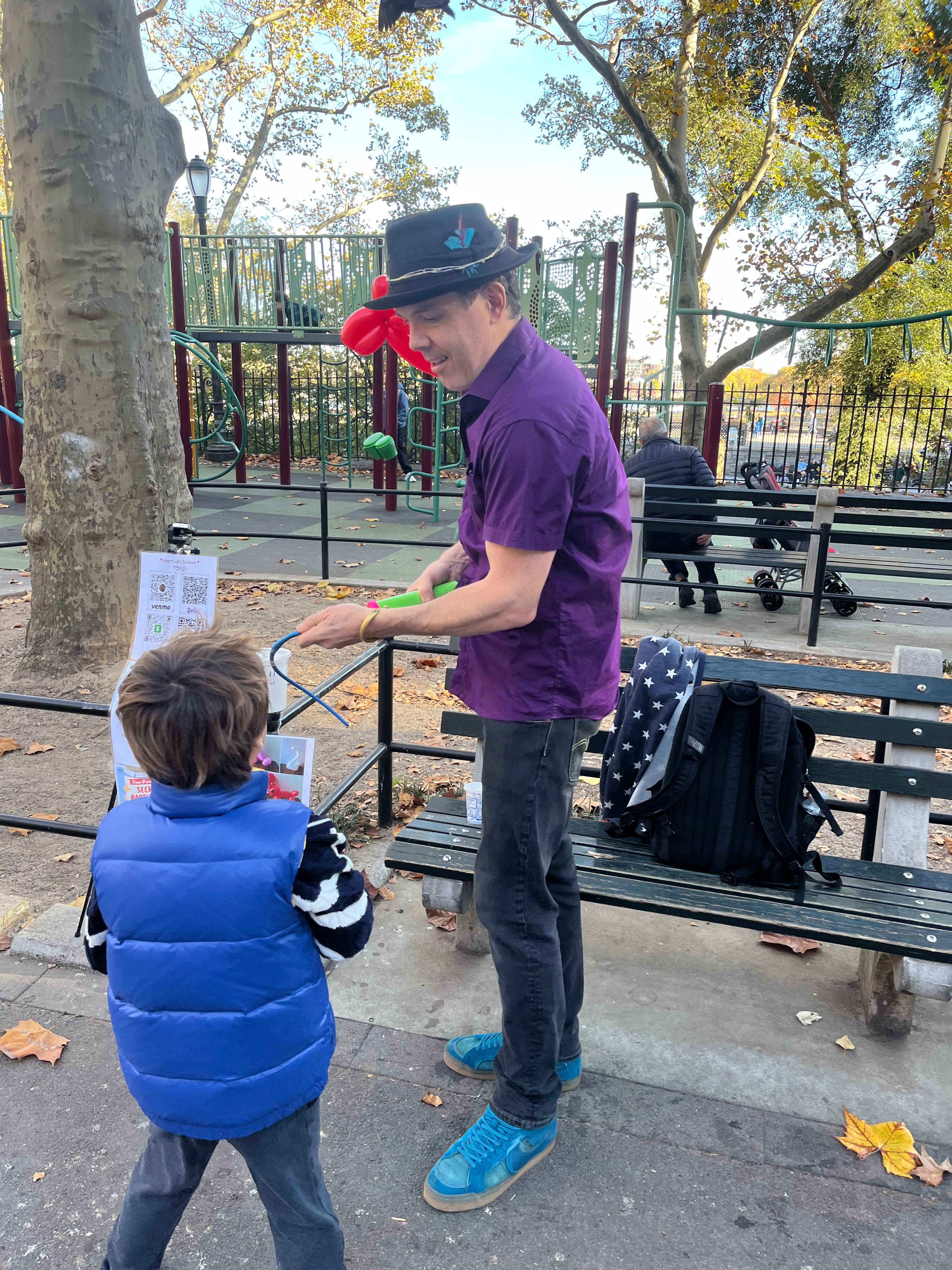 Balloon artist making balloon animals for a child at a New York City playground