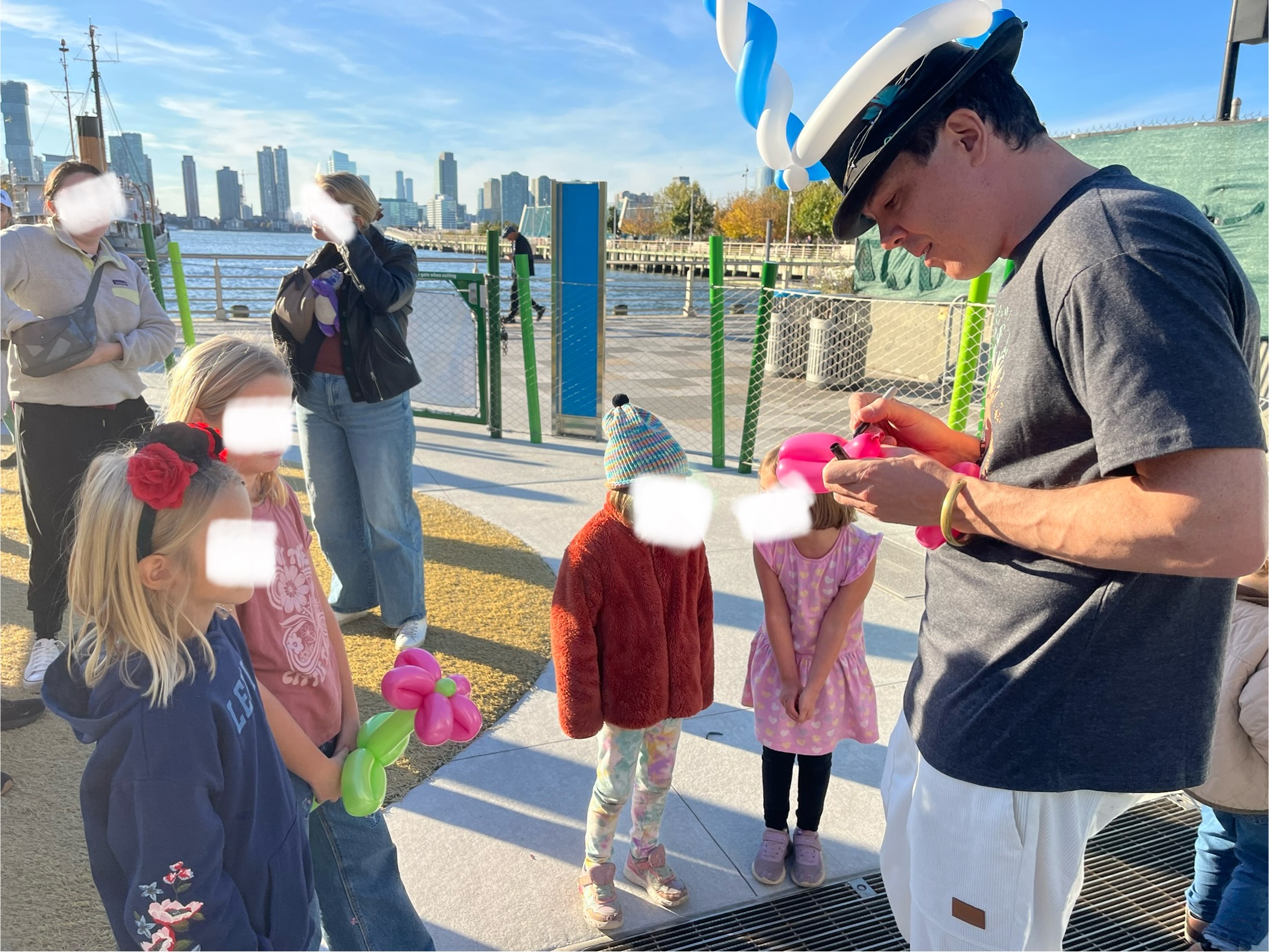 photo of a balloon artist wearing a balloon and making balloon animas for 5 children in a new york city playground